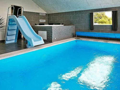 a large swimming pool with a slide in a room at 14 person holiday home in Stege in Stege
