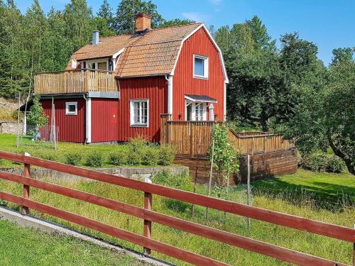 a red house in a field with a fence at 4 person holiday home in STUREFORS in Sturefors