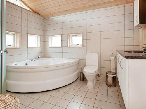 La salle de bains blanche est pourvue d'une baignoire et de toilettes. dans l'établissement Holiday home Asnæs III, à Asnæs