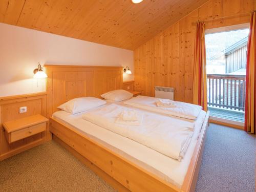 a bedroom with a large bed with a large window at Chalet in Annaberg-Lungötz with a community pool in Annaberg im Lammertal