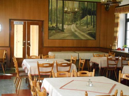 ein Restaurant mit Tischen und Stühlen und einem Gemälde an der Wand in der Unterkunft Gasthaus-Pension Waldesruhe in Schwarzbach