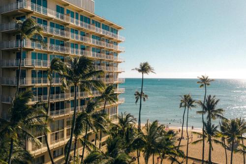a hotel on the beach with palm trees and the ocean at Kaimana Beach Hotel in Honolulu