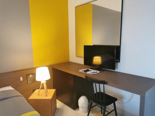 a bedroom with a desk with a television and a bed at Studios FREEBROISE in Saint-François