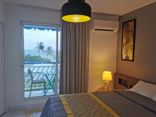 a bedroom with a bed and a balcony with a view at Studios FREEBROISE in Saint-François