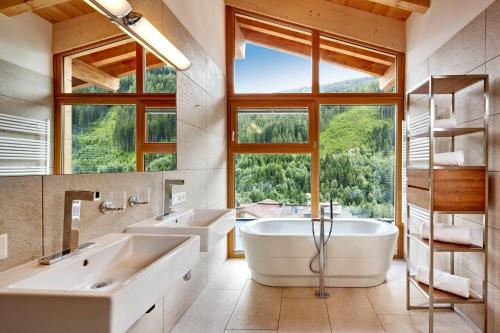 ein Badezimmer mit zwei Waschbecken, zwei Badewannen und einem Fenster in der Unterkunft Gerlos Alpine Estate in Gerlos