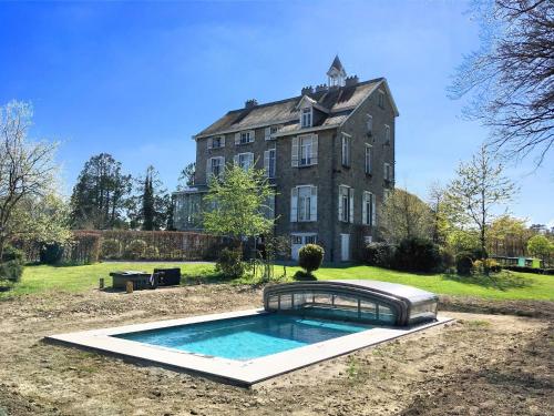 uma casa grande com uma piscina em frente em Beautiful manor house in a park near Rochefort em Forrières