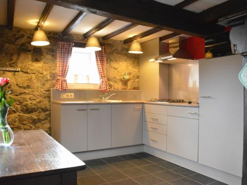 cocina con armarios blancos, fregadero y ventana en Nice gite with low ceilings in Han sur Lesse, en Han-sur-Lesse