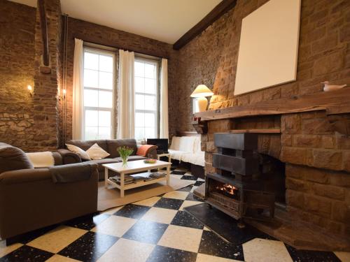 a living room with a brick wall and a fireplace at Charming house perfect for family holidays in Érezée