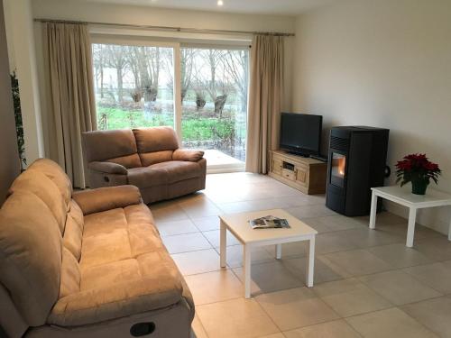 sala de estar con sofá y TV en Soothing Holiday Home with Recreation Room, en Sint-Amands