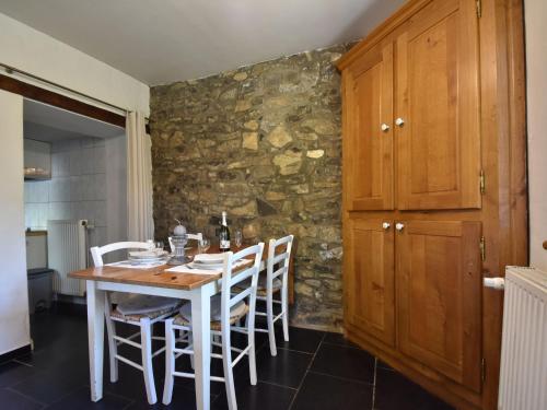 a kitchen with a table and chairs and a stone wall at Charming gite in Les Avins situated by a stream in Modave