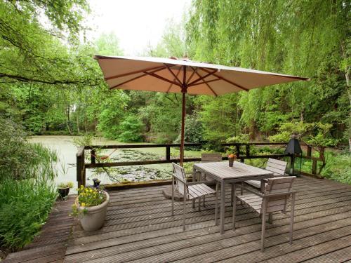 een houten terras met een tafel en een parasol bij Delightful Chalet in Opglabbeek near Lake in Opglabbeek