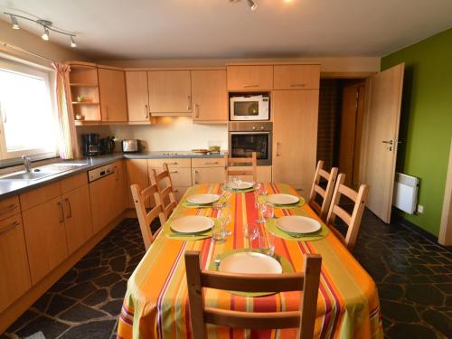 a kitchen with a long table with chairs and a kitchen with green walls at Detached house with breathtaking views in Malmedy