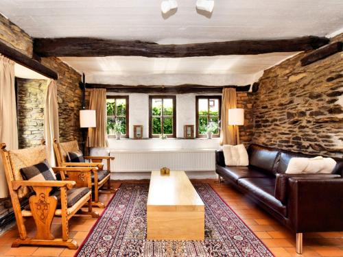 uma sala de estar com um sofá e uma parede de pedra em Romantic holiday house in the Ardennes with garden and view em Nadrin