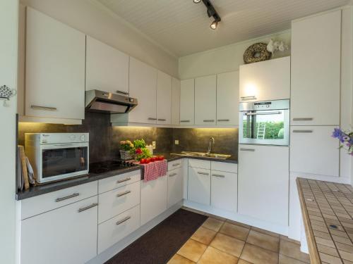 una cocina blanca con armarios blancos y fregadero en Modern Holiday Home in Zingem with Garden, en Zingem