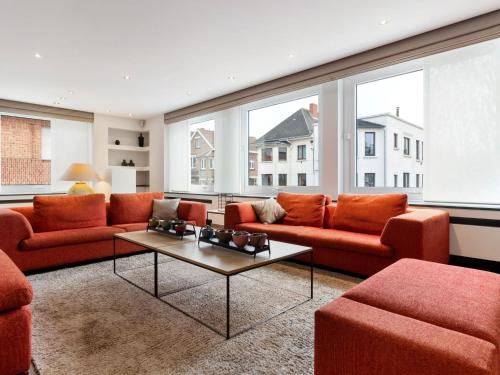 a living room with orange furniture and large windows at Elegant Holiday Home in De Panne with Sauna in De Panne