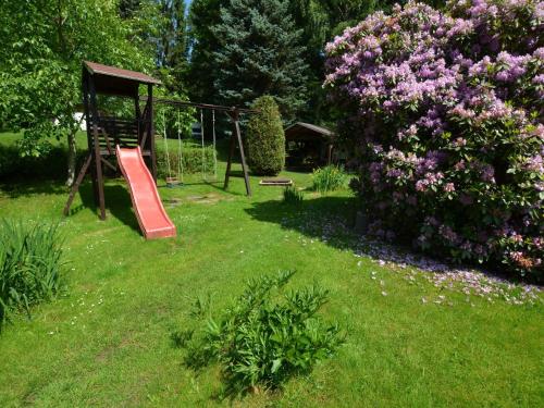 um parque infantil com um escorrega num quintal com flores em Holiday home in Star K e any with fenced garden em Staré Křečany