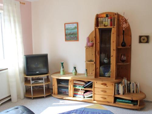 a living room with a tv and a wooden book shelf at Wohnung mit großem Garten an der Ostseeküste in Neubukow