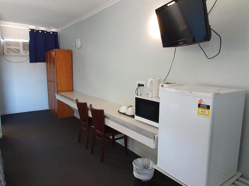 a room with a table with a refrigerator and a tv at Kooyong Hotel in Mackay