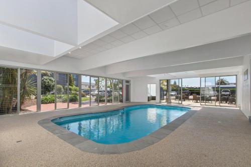 an indoor swimming pool in a house with glass doors at Bellevue On The Lakes in Lakes Entrance