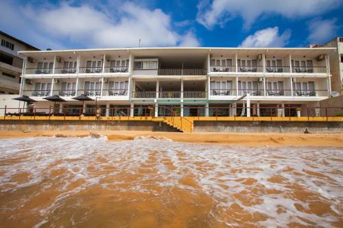 a building on the beach next to a body of water at Coral Rock by Bansei in Hikkaduwa