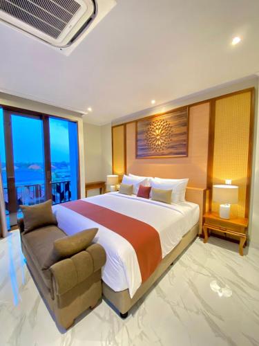 a large bedroom with a large bed and a couch at The Kayangan Sanur in Sanur