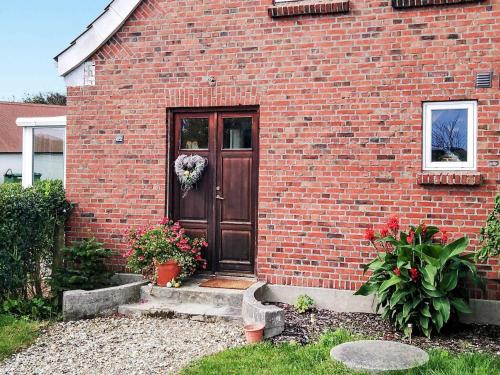 a brick house with a brown door with flowers on it at 4 person holiday home in Lemvig in Harboør