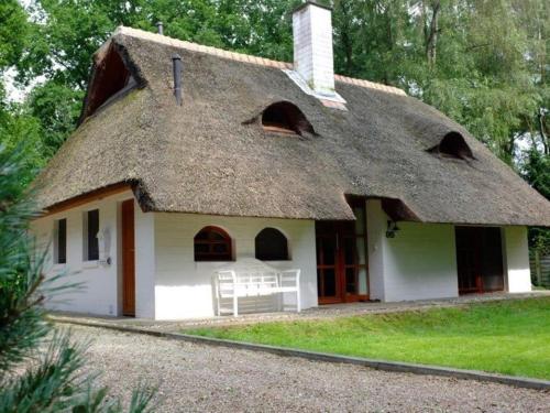 una casa con techo de paja y patio en Exclusive holiday home in Uelsen with conservatory, en Uelsen