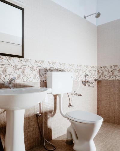 a bathroom with a white toilet and a sink at Runnel View in Masinagudi