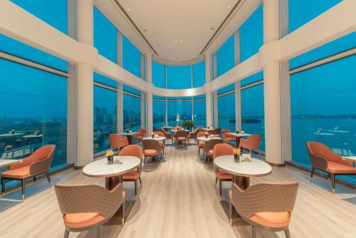 Crowne Plaza Suzhou, an IHG Hotel في سوتشو: مطعم بطاولات وكراسي ونوافذ كبيرة