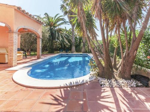 una piscina con palmeras junto a una casa en Belvilla by OYO Nautic Park, en Sant Pere Pescador