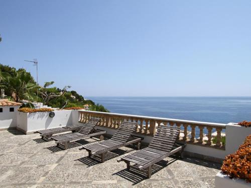 a row of chairs sitting on a balcony overlooking the ocean at Belvilla by OYO Ratjada in Font de Sa Cala