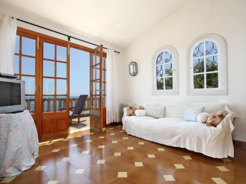 a living room with a white couch and a television at Belvilla by OYO Ratjada in Font de Sa Cala