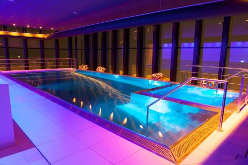 ein großer Pool in einem Gebäude mit lila Beleuchtung in der Unterkunft Fletcher Wellness-Hotel Leiden in Leiden