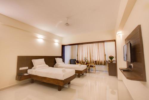 a hotel room with two beds and a flat screen tv at Hotel BMS in Mangalore