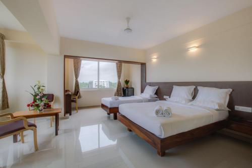 a bedroom with two beds and a large window at Hotel BMS in Mangalore