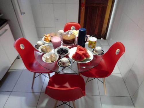 uma mesa com cadeiras vermelhas com comida em Residencial santana em Feira de Santana