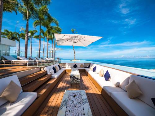 an outdoor patio with white furniture and the ocean at PIER 57 - 211 Luxurious & Modern 1 BR Romantic Zone in Puerto Vallarta