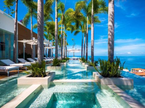 an infinity pool with palm trees and the ocean at PIER 57 - 211 Luxurious & Modern 1 BR Romantic Zone in Puerto Vallarta