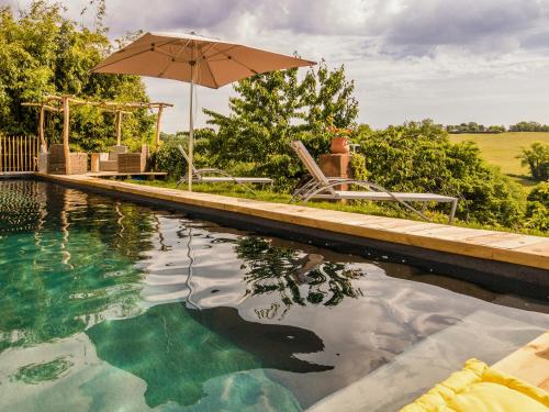 - une piscine avec un parasol, deux chaises et une table dans l'établissement Comfortable g te with swimming pool, à Laval