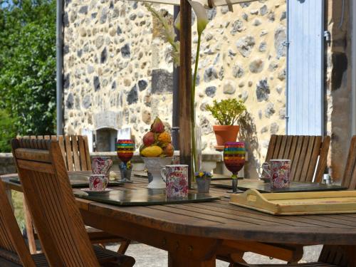 une table en bois sur une terrasse avec des chaises et une table avec un ours en peluche dans l'établissement Holiday Home in Ardèche near Château Ventadour, à Lalevade-dʼArdèche