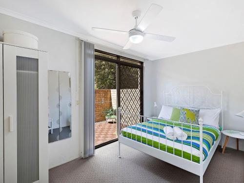 Un dormitorio con una cama y una puerta corrediza de vidrio. en Sundowner Apartment 5, en The Entrance