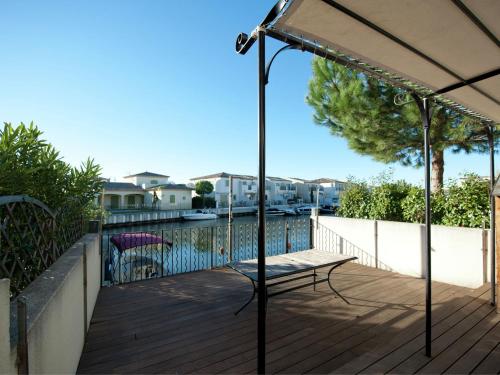 a patio with a bench and an umbrella on a deck at Modern villa near the sea with balcony in Aigues-Mortes