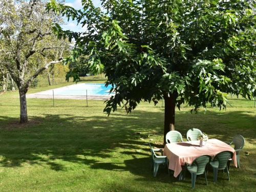 a table and chairs under a tree in a park at Vintage Holiday Home in Besse with Swimming Pool in Saint-Pompont