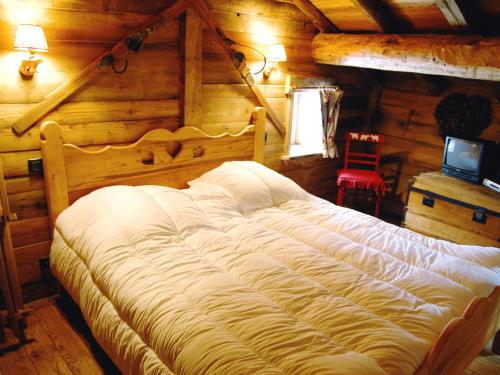 Le VillardにあるCosy Chalet in Champagny-en-Vanoise near Ski Areaのログキャビン内のベッドルーム1室(大型ベッド1台付)