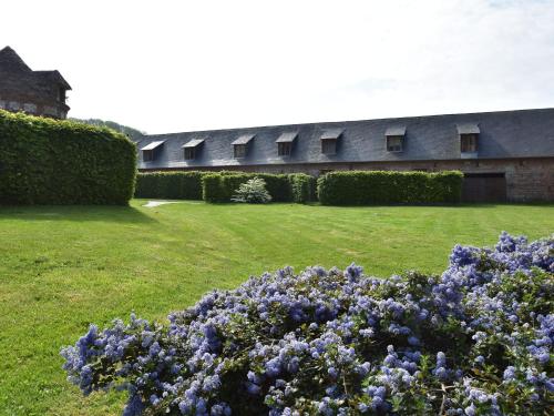 a building with bushes and purple flowers in a yard at Classic Cottage in Le Bourg Dun with Garden in Le Bourg-Dun