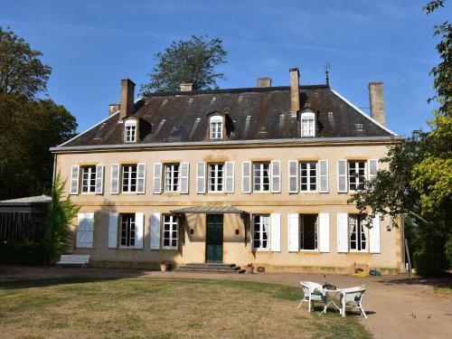 uma casa grande com duas cadeiras em frente em Vintage Mansion in Saint Aubin sur Loire with Pool em Bourbon-Lancy