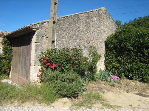 un bâtiment en pierre avec des fleurs roses devant lui dans l'établissement Comfortable g te in Oppede France, à Oppède