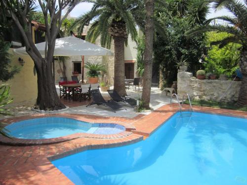 GiannoudiにあるAttractive Villa in Giannoudi with Private Poolのレンガ造りのパティオとヤシの木がある青い大型スイミングプール
