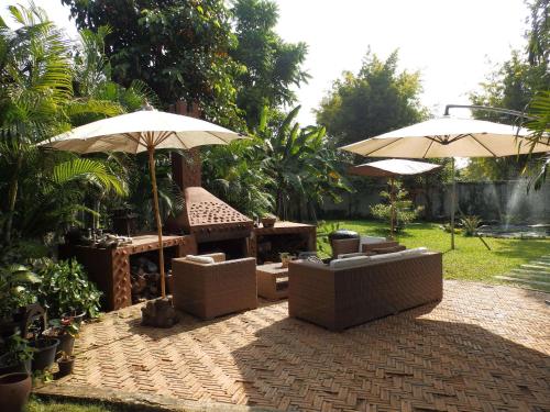 a patio with umbrellas and couches and a table at Rice Barn And Rooms in Hang Dong
