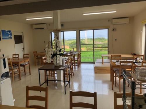 a dining room with tables and chairs and windows at VistaMare in Kanoya